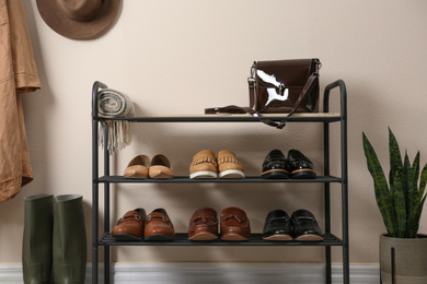 Photo of Rack with different shoes near beige wall in room