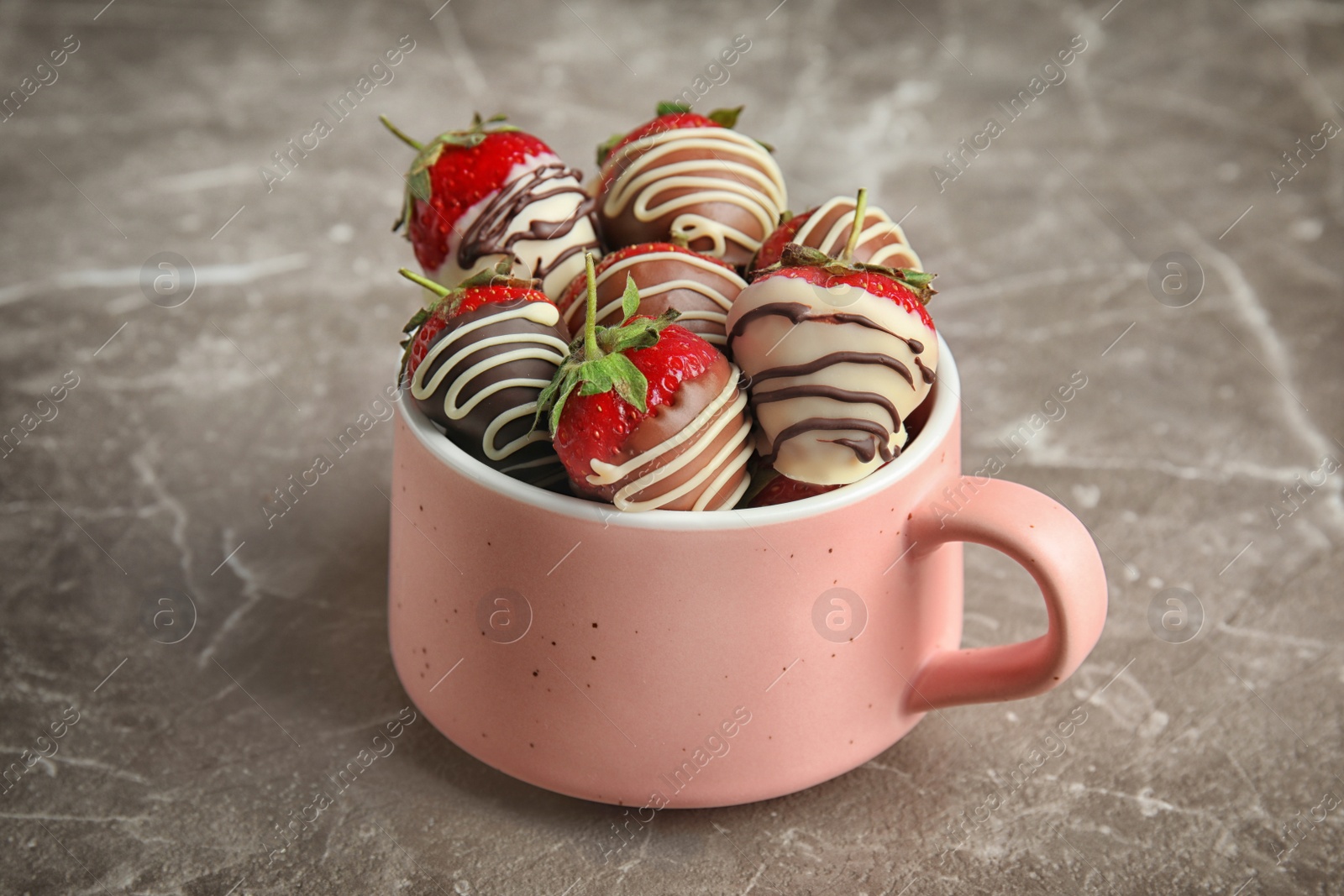 Photo of Cup with chocolate covered strawberries on grey background