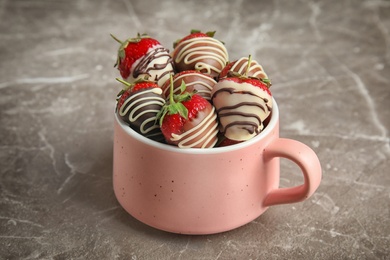 Cup with chocolate covered strawberries on grey background