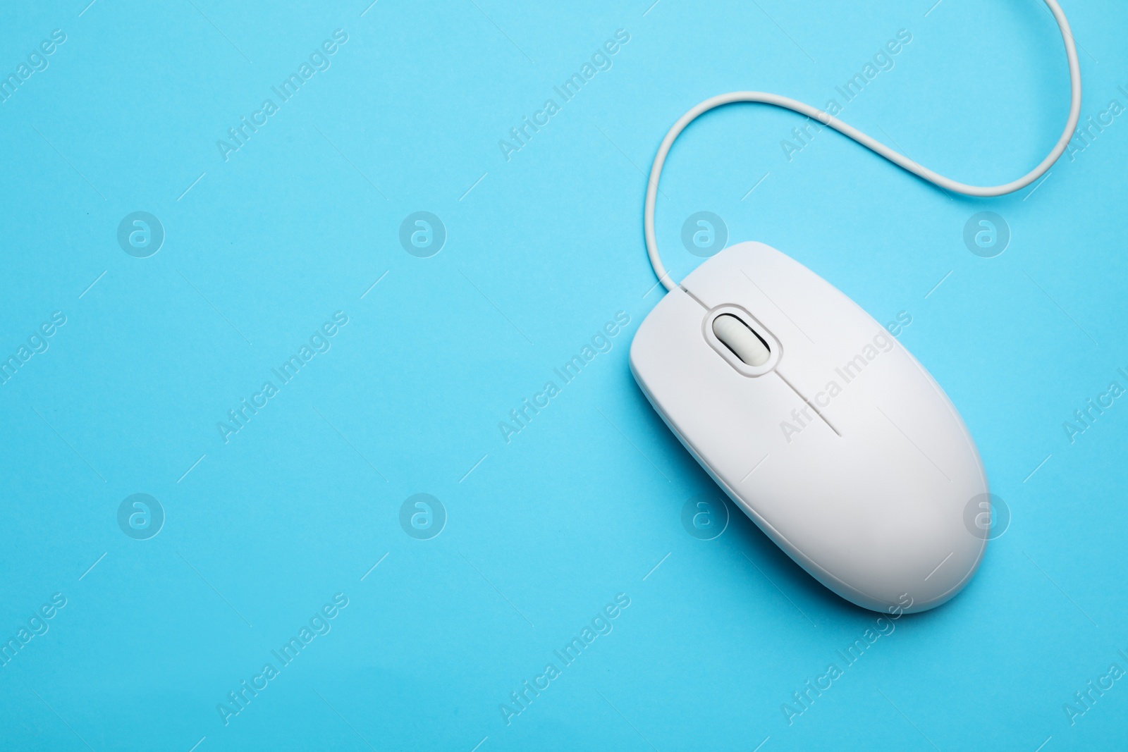 Photo of Wired computer mouse on light blue background, top view. Space for text