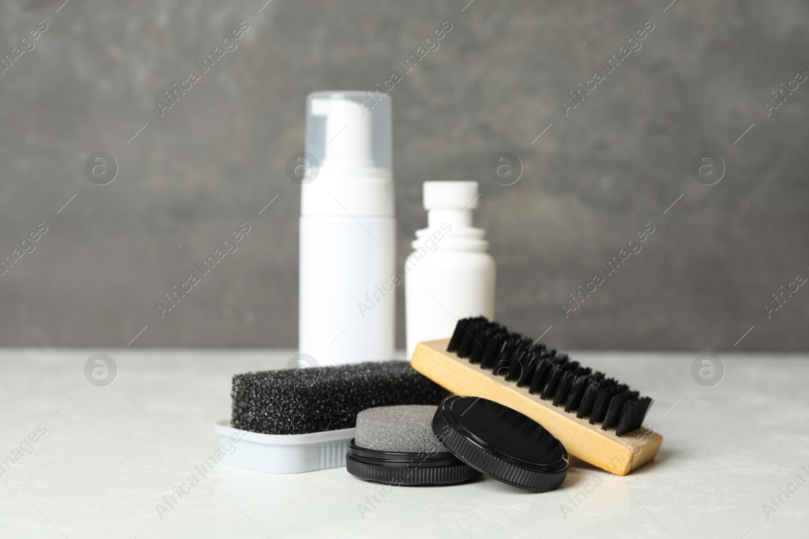 Photo of Composition with shoe care accessories on white table against grey background