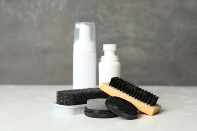 Composition with shoe care accessories on white table against grey background