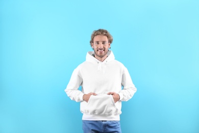 Portrait of man in hoodie sweater on color background. Space for design