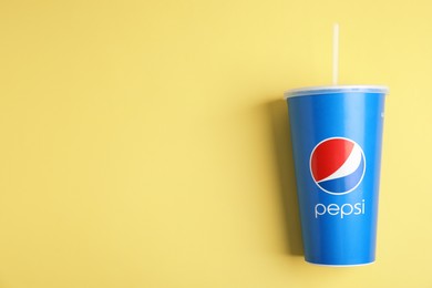 Photo of MYKOLAIV, UKRAINE - JUNE 08, 2021: Paper Pepsi cup on yellow background, top view. Space for text