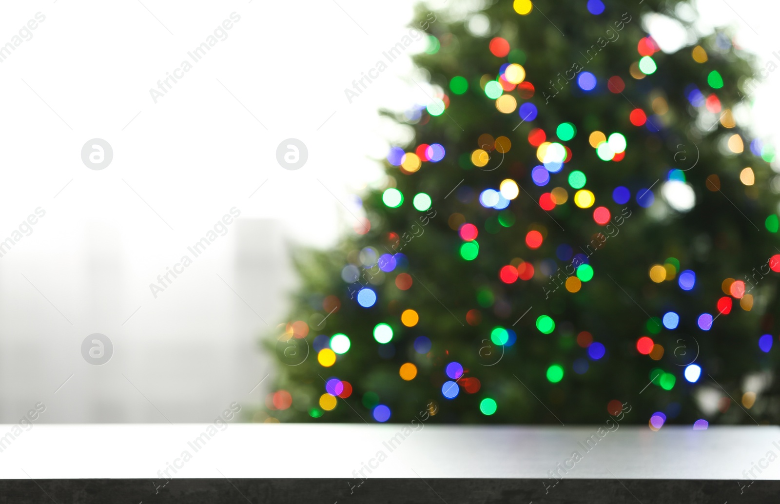 Photo of Empty table and blurred fir tree with colorful Christmas lights on background, bokeh effect. Space for design