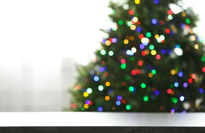 Photo of Empty table and blurred fir tree with colorful Christmas lights on background, bokeh effect. Space for design