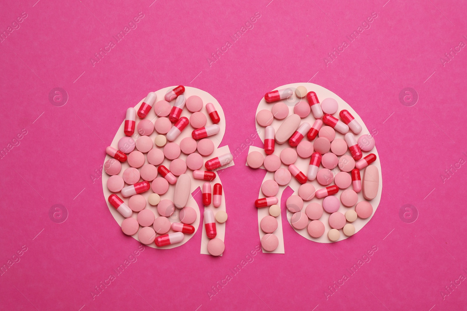 Photo of Paper cutout of kidneys with pills on magenta background, top view