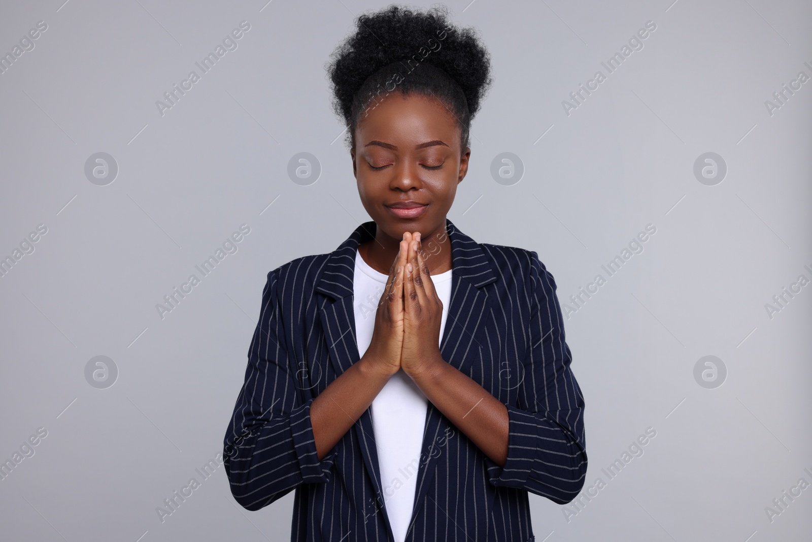 Photo of Woman with clasped hands praying to God on light grey background