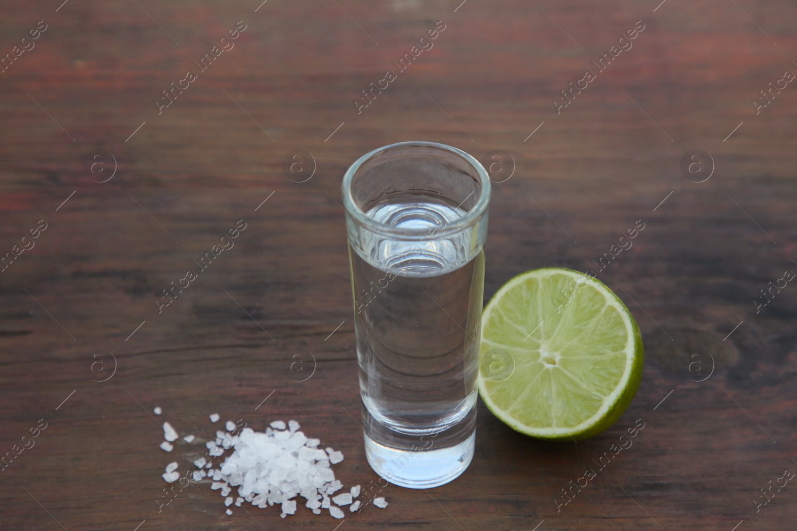 Photo of Mexican tequila shots with lime and salt on wooden table