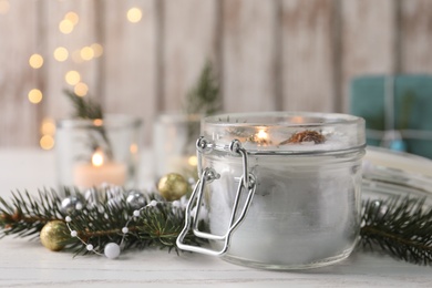Burning scented conifer candle and Christmas decor on white wooden table. Space for text