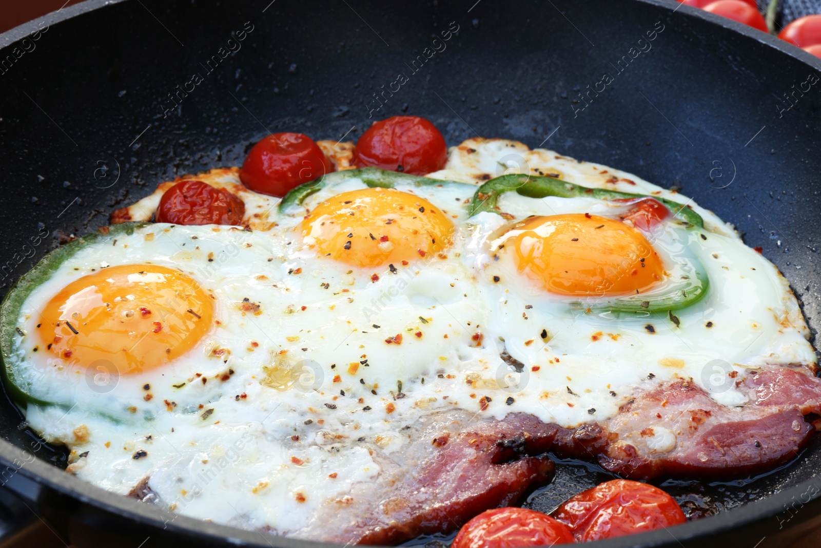 Photo of Delicious fried eggs with bacon, tomatoes and pepper in frying pan, closeup