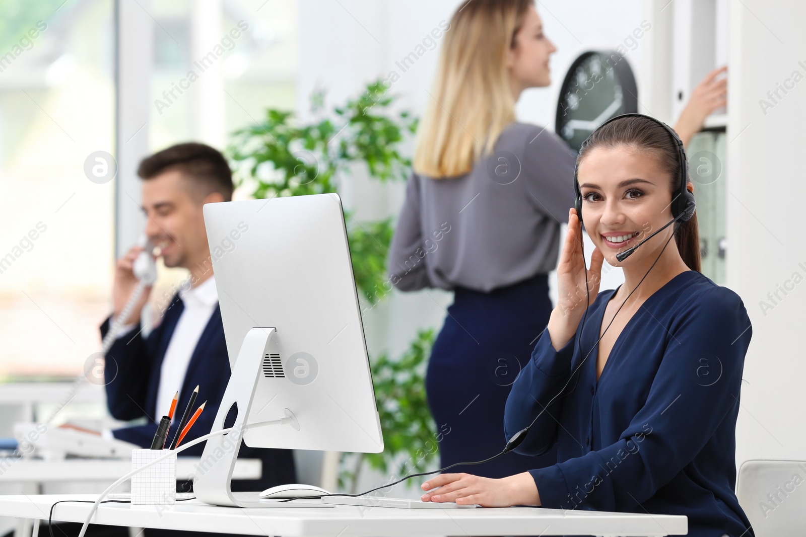 Photo of Female receptionist with headset at desk in office