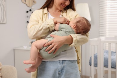 Photo of Mother holding her sleeping newborn baby in child`s room, closeup