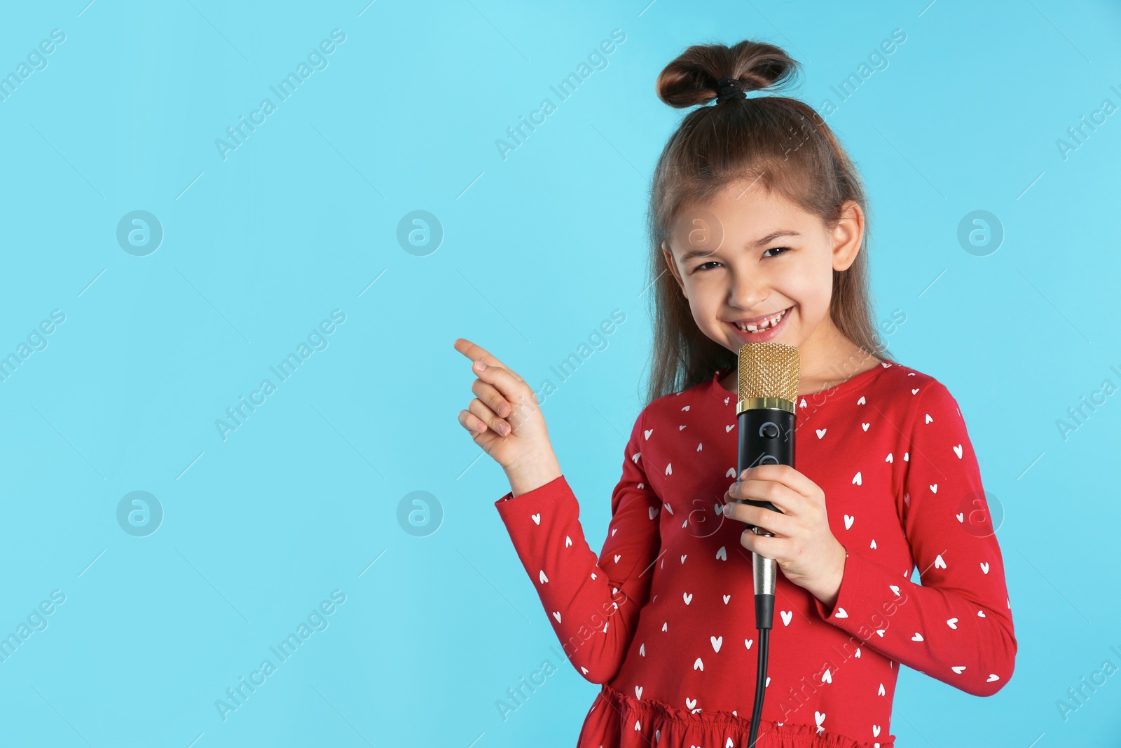Photo of Cute funny girl with microphone on color background. Space for text