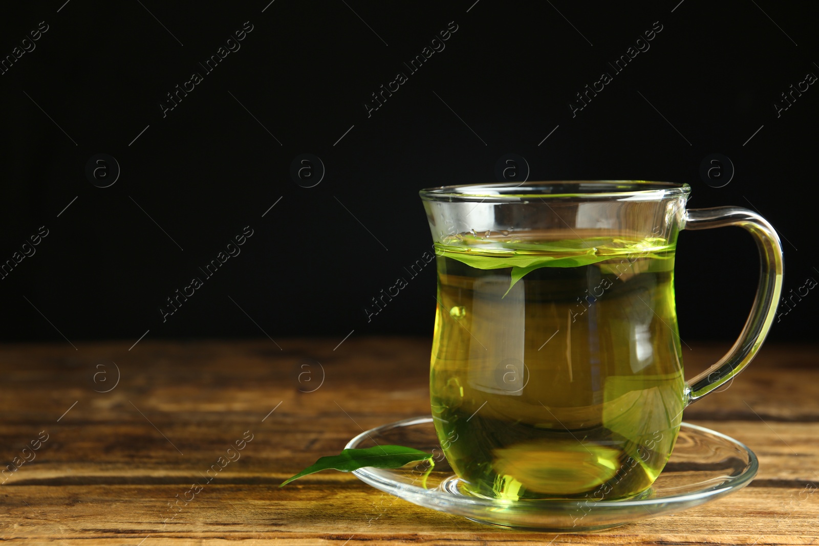 Photo of Cup of aromatic green tea on wooden table. Space for text