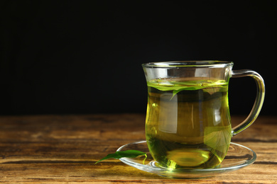 Photo of Cup of aromatic green tea on wooden table. Space for text