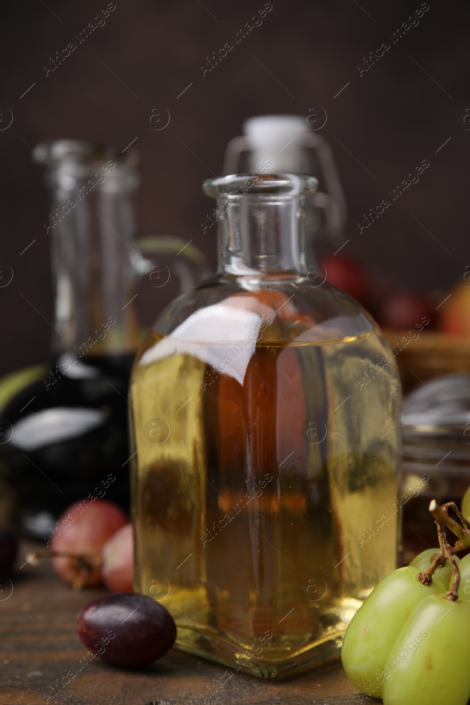 Photo of Vinegar in glass bottle and grapes on wooden table