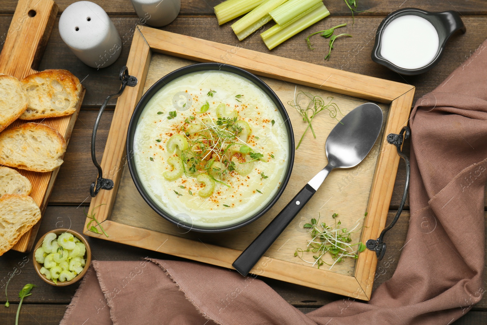 Photo of Bowl of delicious celery soup served on wooden table, flat lay