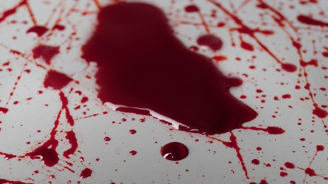Photo of Stain and splashes of blood on light grey background, closeup