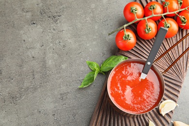 Photo of Flat lay composition with pan of sauce and tomatoes on grey table. Space for text