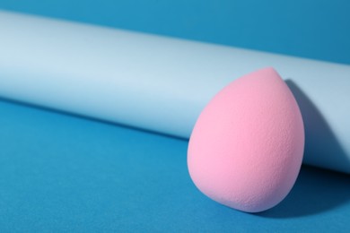 Photo of Pink makeup sponge on light blue background, closeup. Space for text