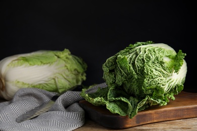 Photo of Fresh ripe Chinese cabbages on wooden table against black background