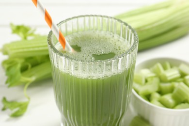 Glass of celery juice and fresh vegetables on white table, closeup
