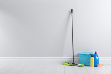 Photo of Mop and cleaning supplies on floor indoors, space for text