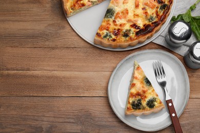 Photo of Delicious homemade salmon quiche with broccoli, fork and salt shakers on wooden table, flat lay. Space for text