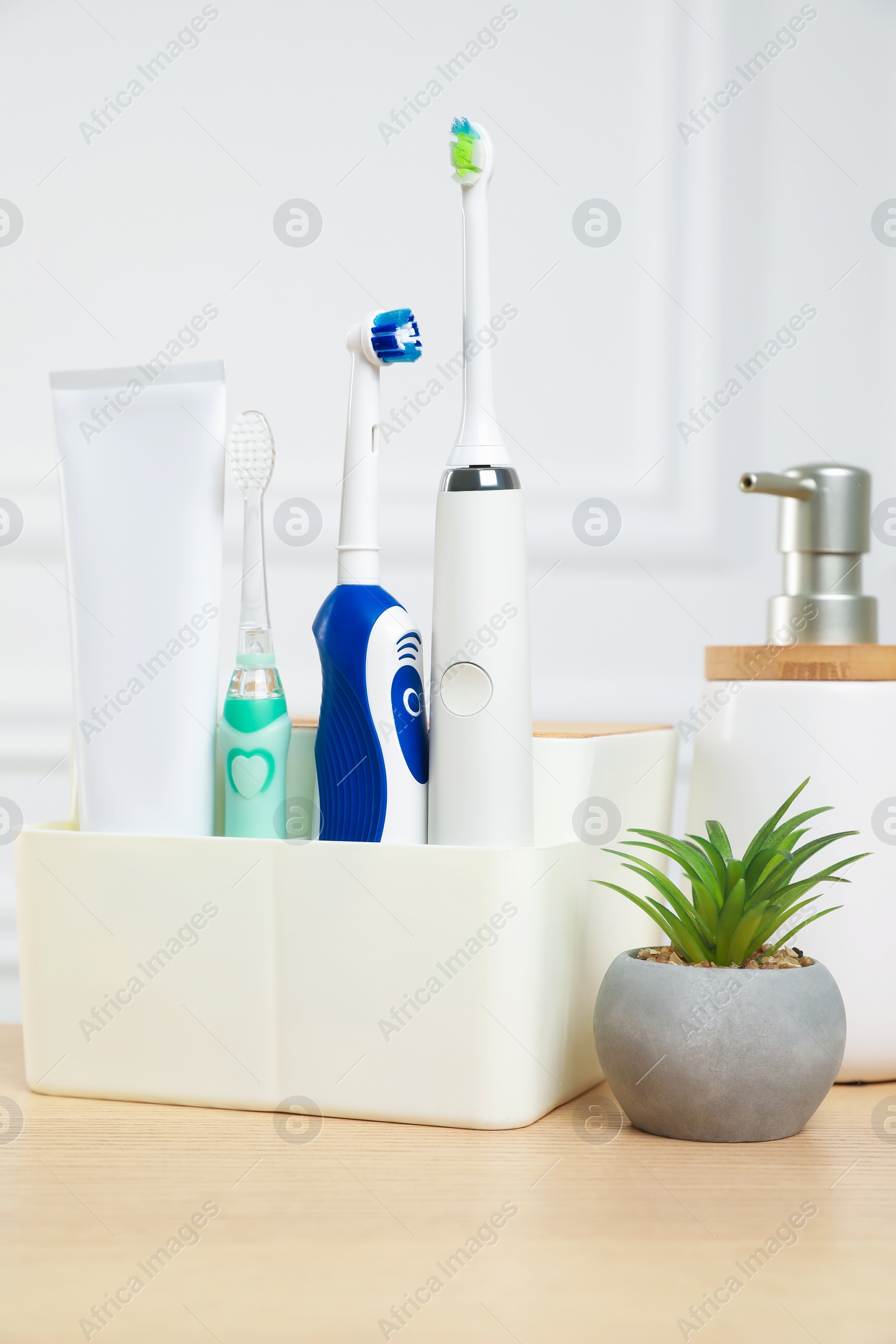 Photo of Electric toothbrushes and soap dispenser on wooden table
