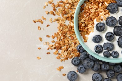 Bowl of yogurt with granola and blueberries on grey marble table, flat lay. Space for text