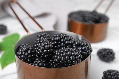 Photo of Metal saucepan with tasty ripe blackberries on table, closeup
