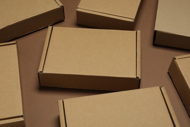 Photo of Many closed cardboard boxes on brown background, closeup