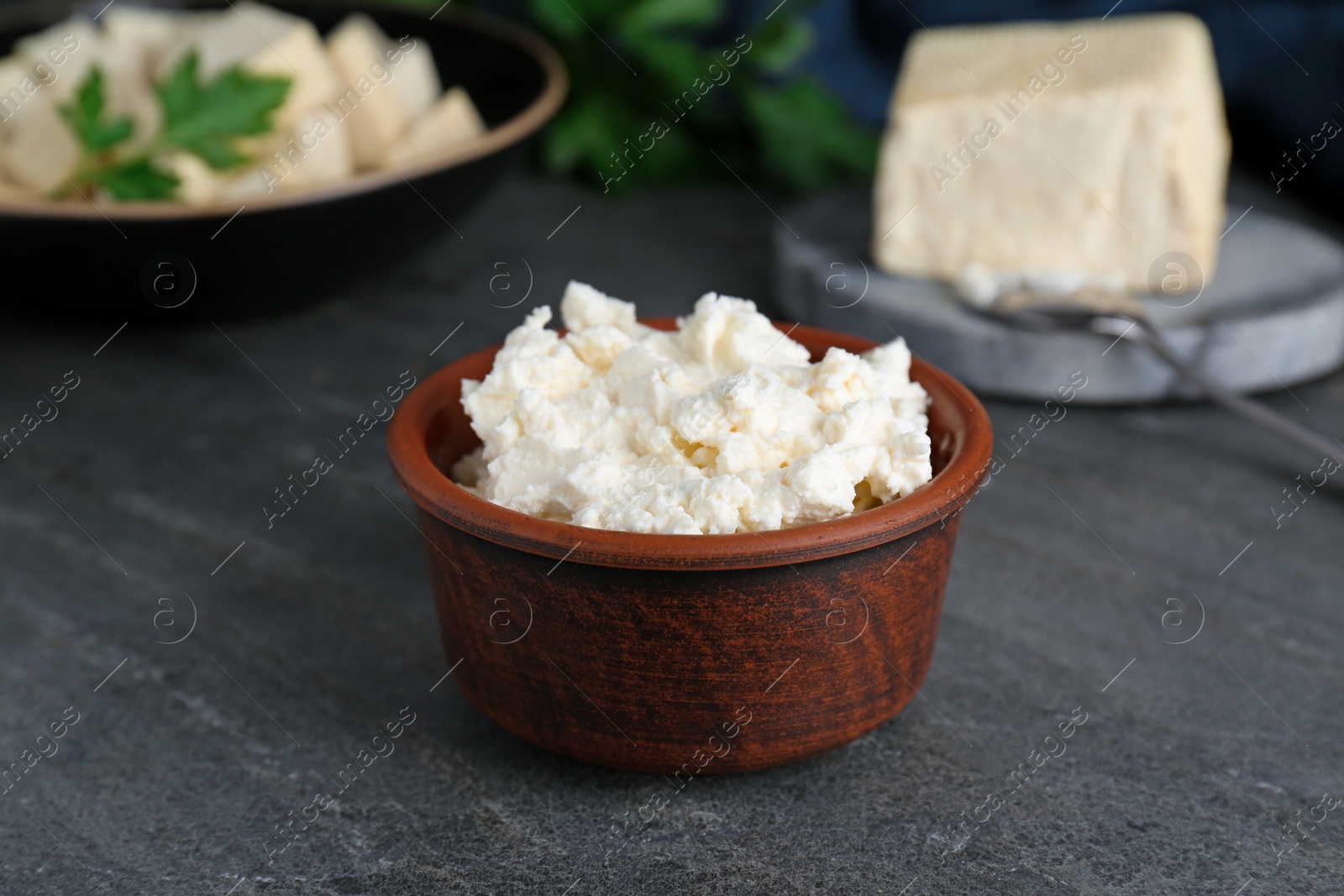 Photo of Delicious tofu cream cheese in bowl on black table, closeup