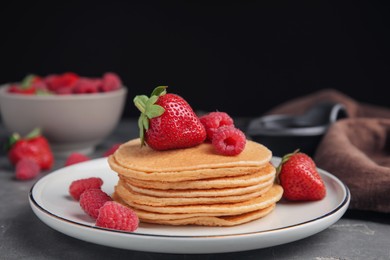 Photo of Tasty pancakes with fresh berries on grey table