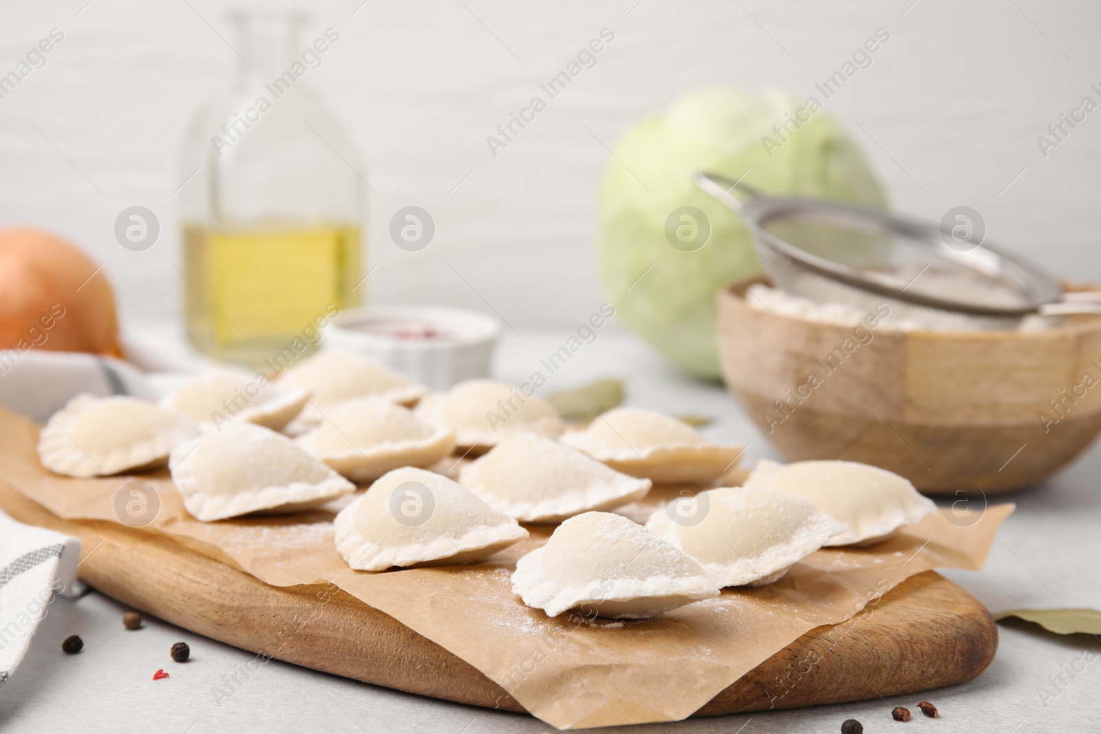 Photo of Raw dumplings (varenyky) with tasty filling on light grey table, closeup