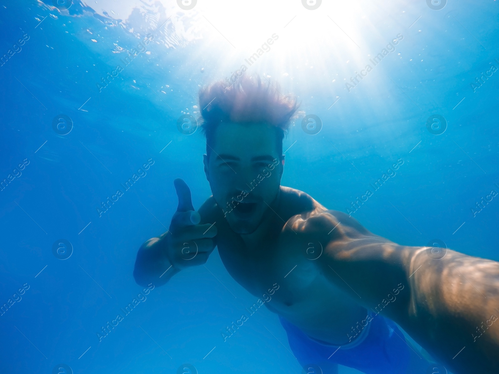 Photo of Handsome young man swimming in pool, underwater view