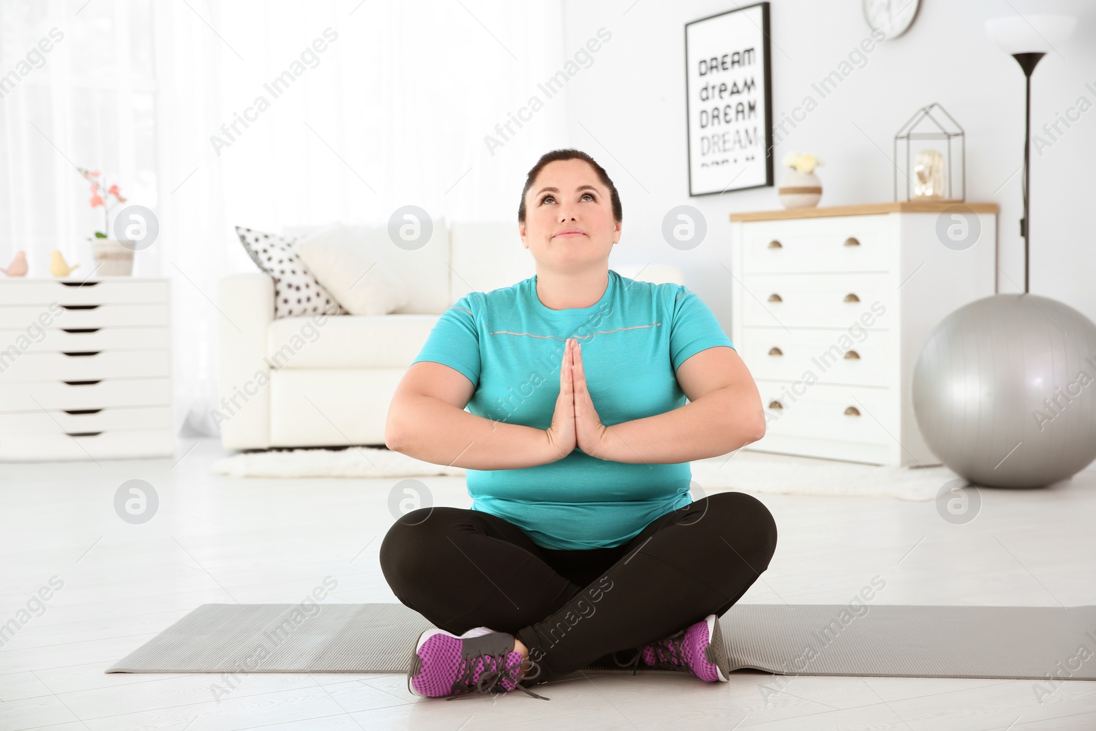 Photo of Overweight young woman practicing yoga at home