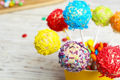 Photo of Tasty cake pops in cup on table, closeup. Space for text