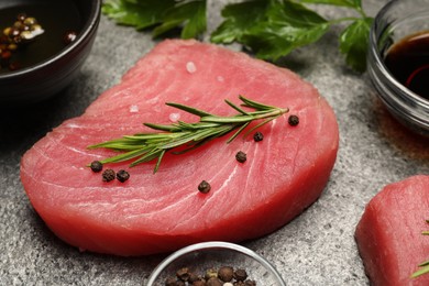 Raw tuna fillet with herbs and spices on gray table, closeup