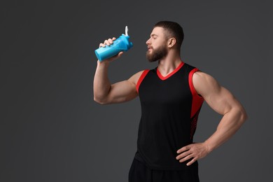 Young man with muscular body holding shaker of protein on grey background, space for text