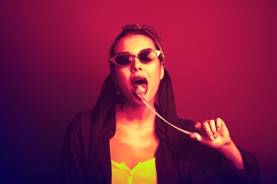 Fashionable young woman with chewing bubblegum in neon lights