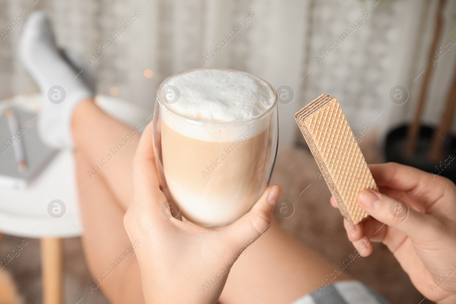 Photo of Woman having delicious wafer and coffee for breakfast indoors, closeup