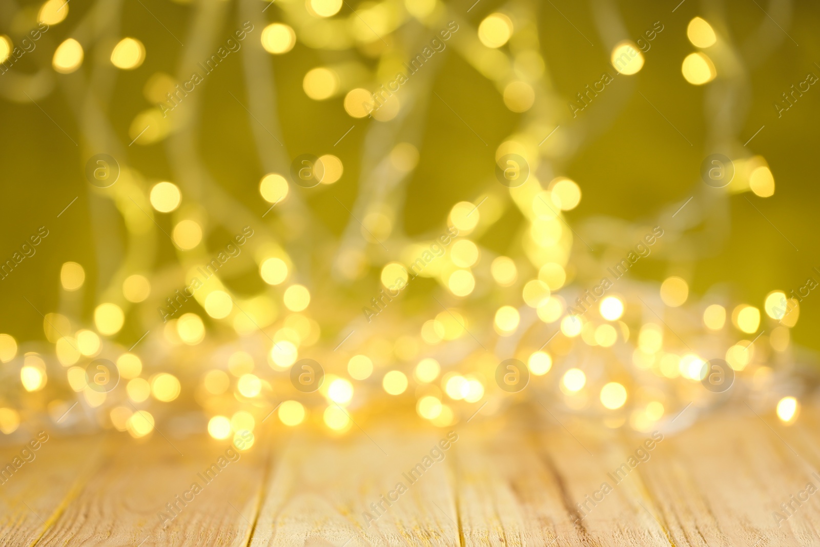 Photo of Yellow Christmas lights on wooden table, blurred view