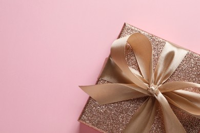 Gift box with bow on pink background, top view. Space for text