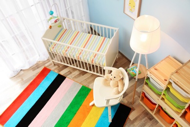 Photo of Modern interior of light cozy baby room with crib, view from above