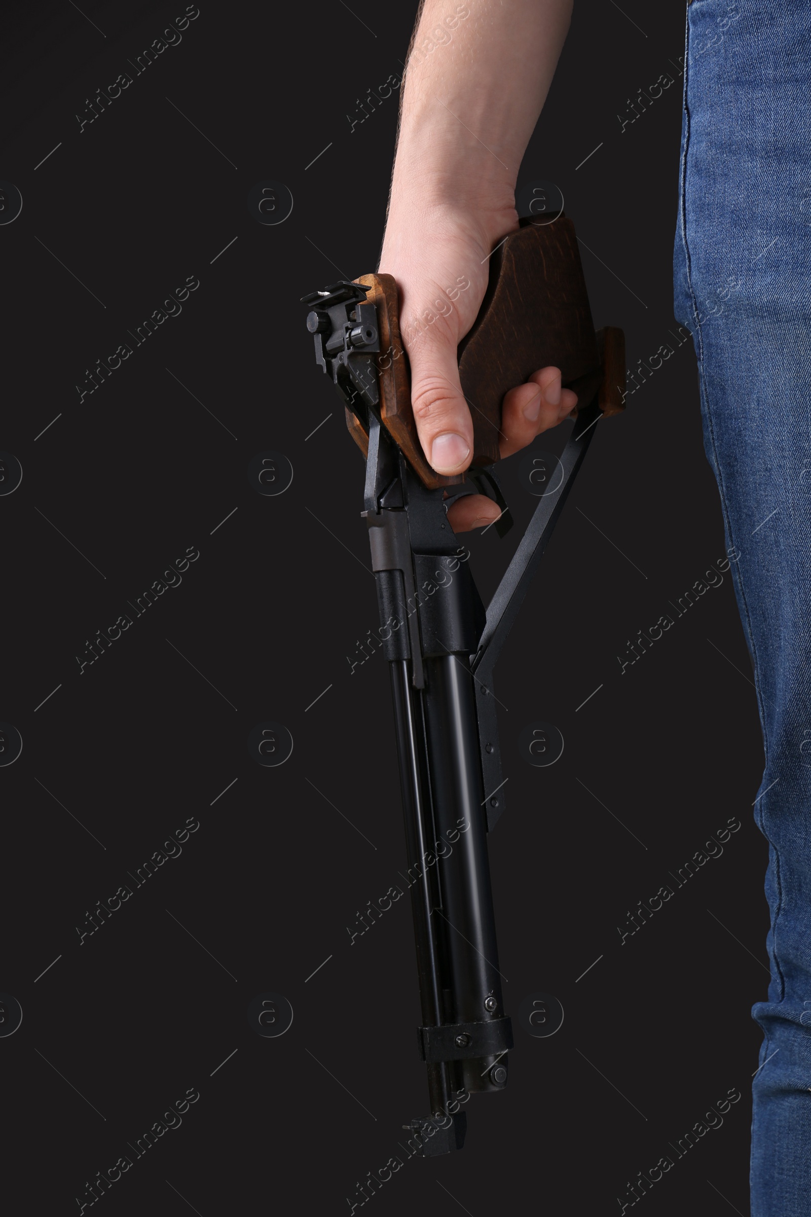 Photo of Gun shooting sport. Man holding standard pistol on dark background, closeup