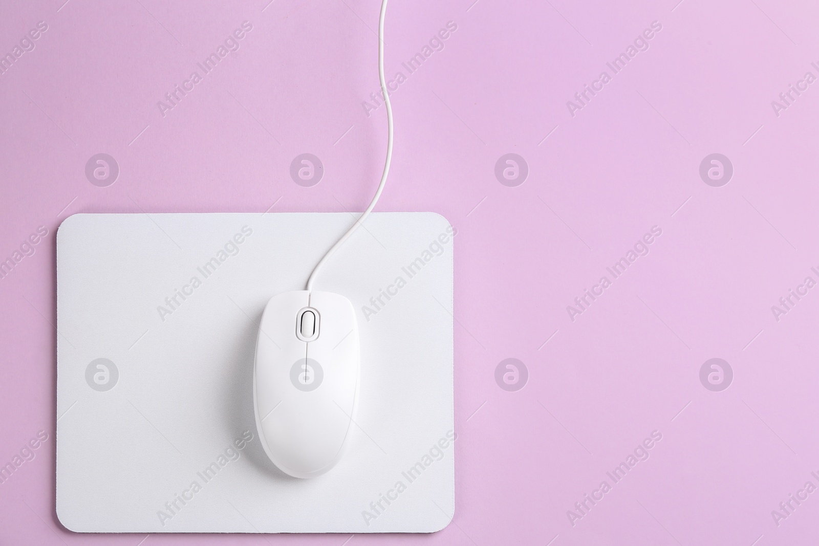 Photo of Modern wired optical mouse and pad on lilac background, top view. Space for text