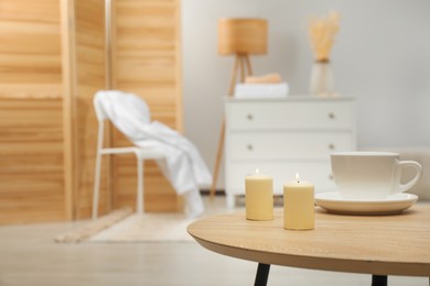 Photo of Wooden table with candles and cup, space for text. Interior design