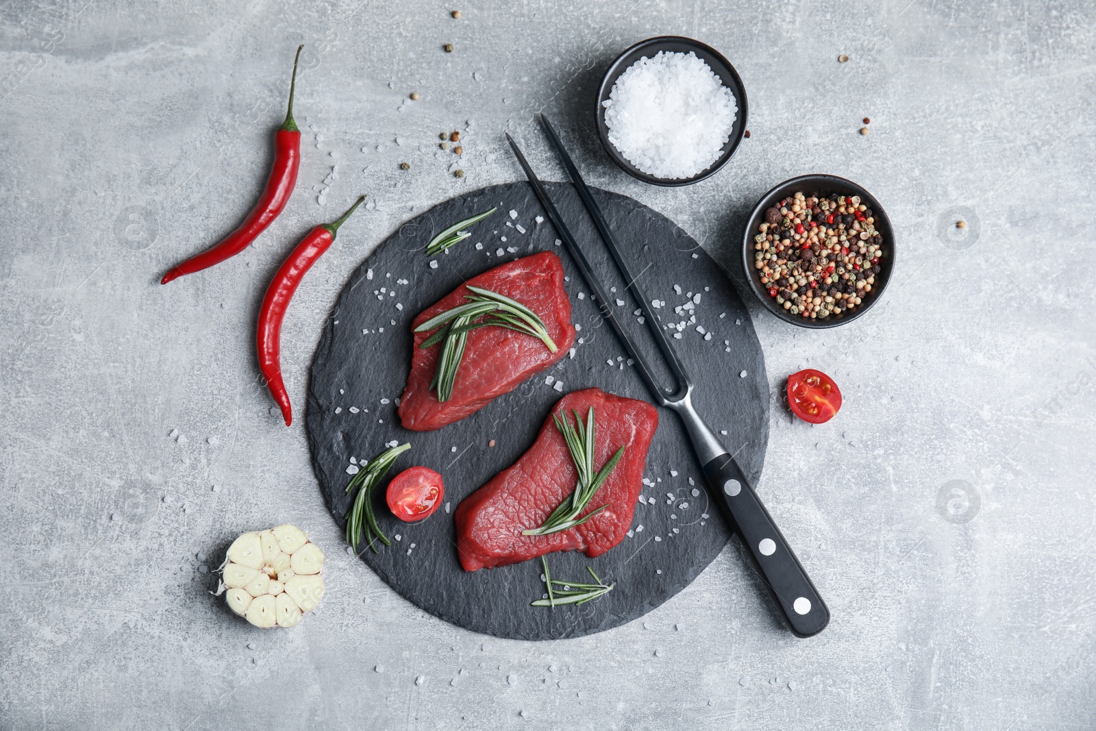 Photo of Fresh raw meat steaks and spices on light grey table, flat lay